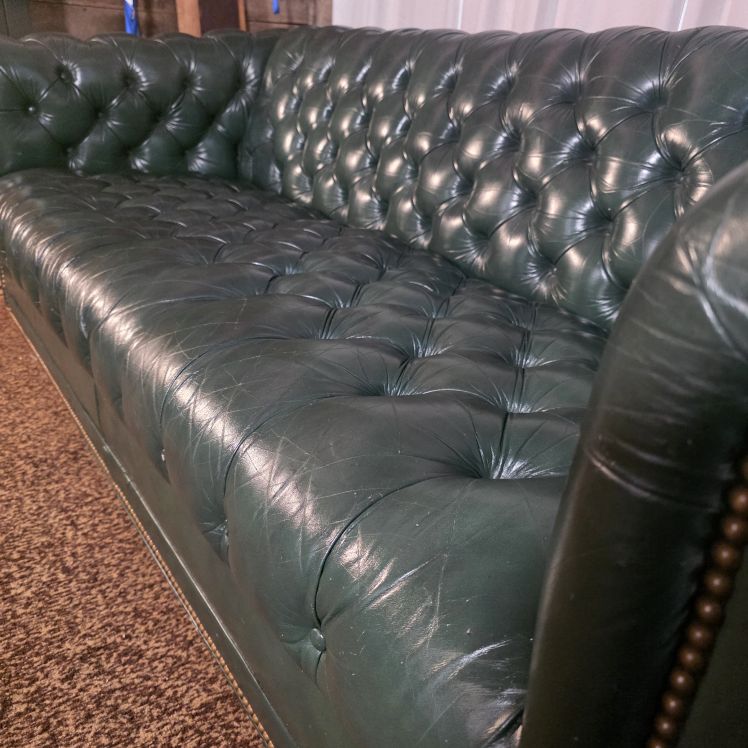 Close-up of tufted green leather seat and back showing light surface marks